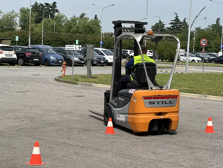 Operatore guida un carrello elevatore in un'area delimitata da coni durante una prova pratica